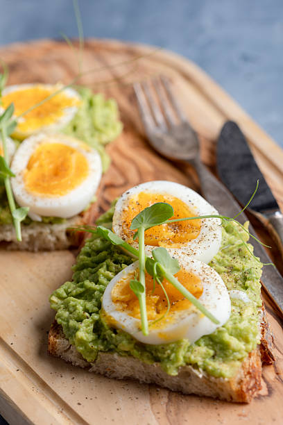 istock Avocado toast with softboiled eggs on wooden board 2257733143