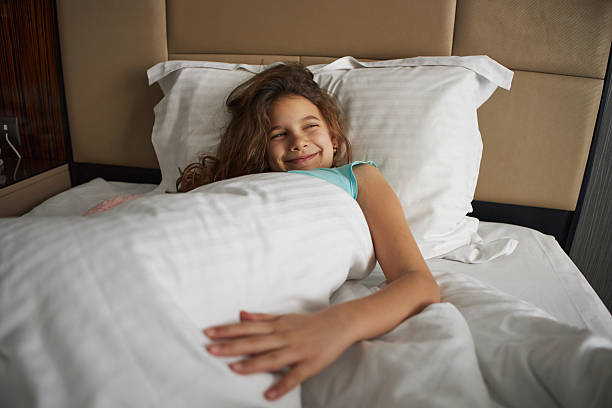 Scared little girl watching a horror movie on TV during morning time with her family in bed.