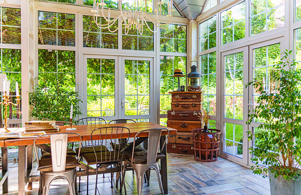 Living room design that seamlessly integrates the indoors with the lush outdoors. Surrounded by towering trees visible through floor-to-ceiling glass walls.