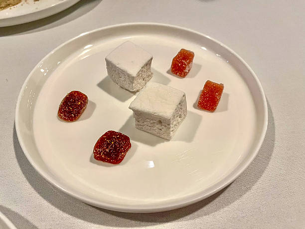 Two Pillowy White Marshmallow-like Confections and Three Vibrant Sugared Fruit Jellies Artfully Arranged on a Pristine White Plate.