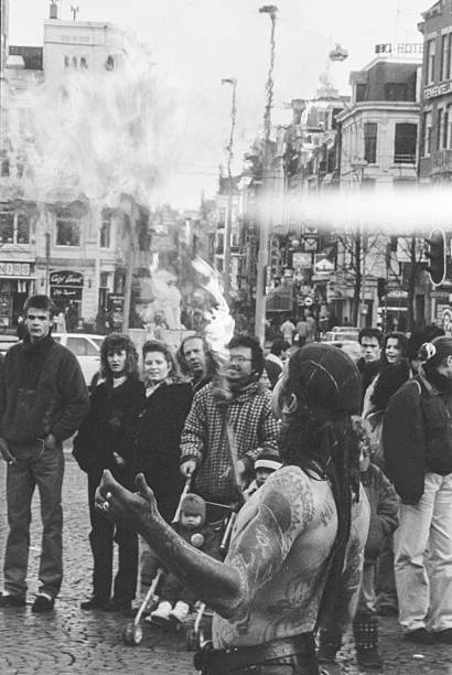 A street performer breathes fire as a crowd watches at Leidseplein in Amsterdam, March 1991. Street entertainment was a common sight in the city centre during the early 1990s, reflecting the lively urban atmosphere of the time. maart 1991, Leidseplein, Amsterdam, The Netherlands