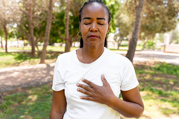 istock Woman meditating in park, eyes closed, hand on chest, practicing mindfulness and deep breathing for well-being 2257762497