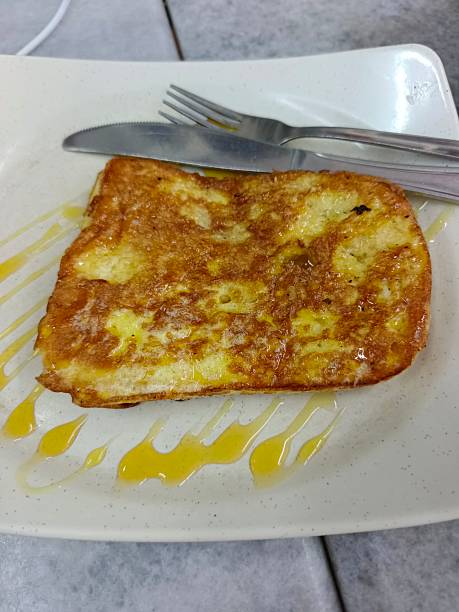 Golden brown French toast served with syrup on a white plate, highlighting texture, sweetness, and breakfast appeal