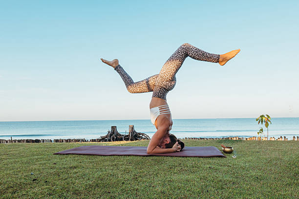Woman practicing yoga on the beach, wellness and healthy lifestyle concept. Young woman performs a yoga pose on the sand, dressed in athletic or yoga attire, with a calm ocean or sea backdrop. Bright natural light, sunrise or sunset, and a peaceful beach environment create a relaxing and inspiring atmosphere. Perfect for stock photography related to yoga, meditation, fitness, mindfulness, wellness, healthy living, active lifestyle, outdoor exercise, vacation relaxation, beach fitness, lifestyle content, and travel. Ideal for use in wellness marketing, lifestyle blogs, yoga campaigns, fitness promotions, social media content, travel advertising, and inspirational or motivational visuals.