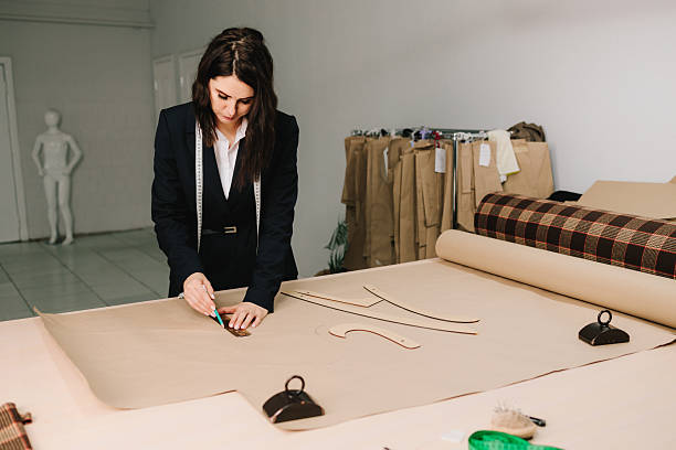 Designer uses garment drafting tools and pattern pieces to create clothing on fabric paper