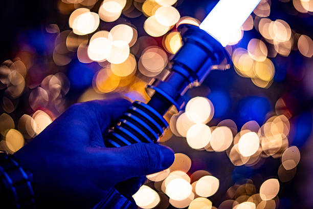 Close-up of a glowing futuristic light sword held in a hand with colorful bokeh lights in the background, creating a fantasy and sci-fi inspired atmosphere.