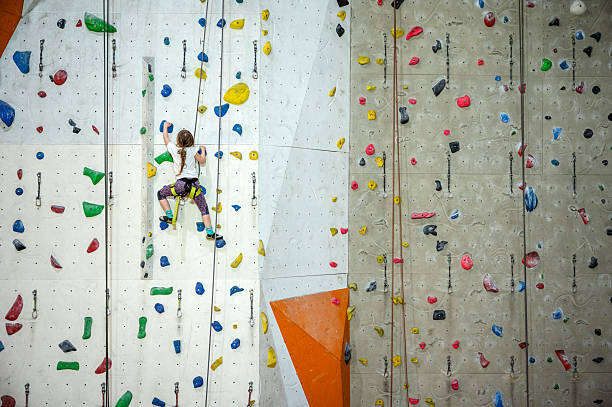 An unrecognisable child climbs up a high climbing wall.