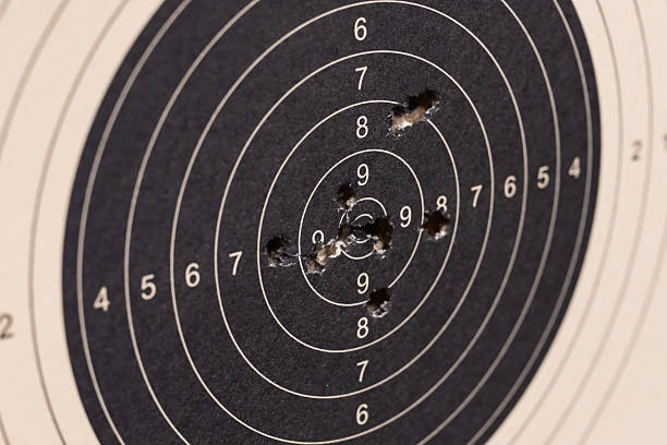 Close-up of a paper shooting target with multiple bullet holes in the black bullseye area representing precision, accuracy, and practice.