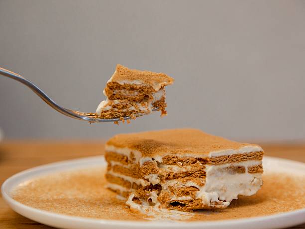 istock Honey Cake Mille feuille pastry slice on a white plate with cinnamon dusting, minimal cafe dessert photography, top view, wooden table 2257801415