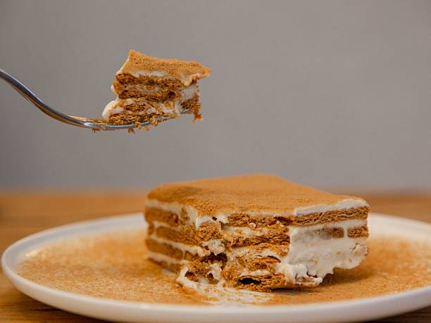 istock Honey Cake Mille feuille pastry slice on a white plate with cinnamon dusting, minimal cafe dessert photography, top view, wooden table 2257801417
