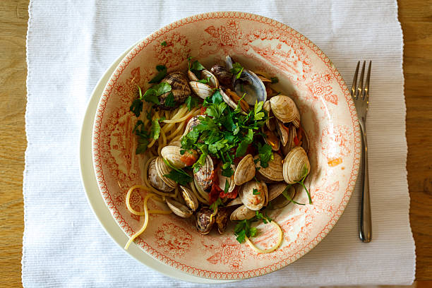 Fork and plate with spaghetti pasta and shells and fresh parsley