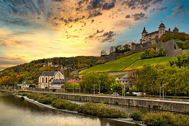 Wuerzburg, Germany - October 16, 2025: Marienberg Fortress in an autumnal vineyard. St. Burkard's Church is on the left.