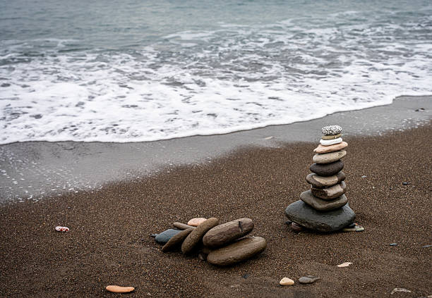 Single stack of balanced zen stones on a sandy beach with sea waves background