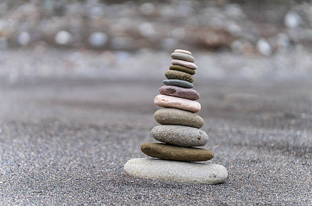 Single stack of balanced zen stones on a sandy beach with sea waves background