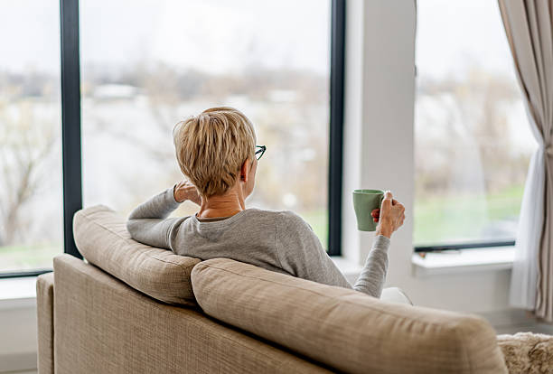 Woman relaxing at home with coffee looking out window