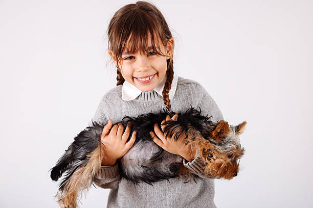 Love between pet and little owner, little and Yorkshire Terrier cuddling at house