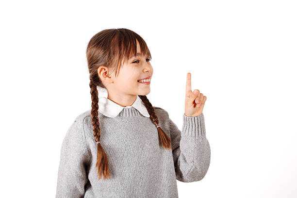 Brunette hispanic girl wearing grey sweater with a big smile on face, pointing with hand and finger to the side looking at the camera.