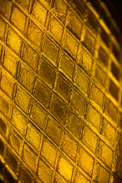 A vivid close-up of a yellow metal surface with diamond shaped texture, emphasising rough texture and diagonal grid lines.