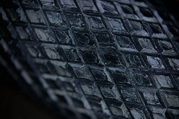 A vivid close-up of a black painted metal surface with diamond shaped texture, emphasising rough texture and diagonal grid lines.