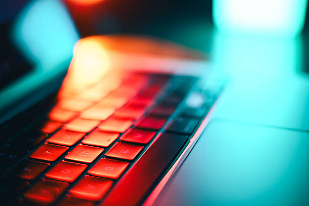 Laptop keyboard glowing with vibrant red and blue neon light, showing modern technology