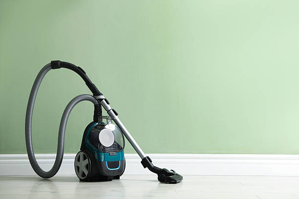 One vacuum cleaner on floor near green wall. Space for text