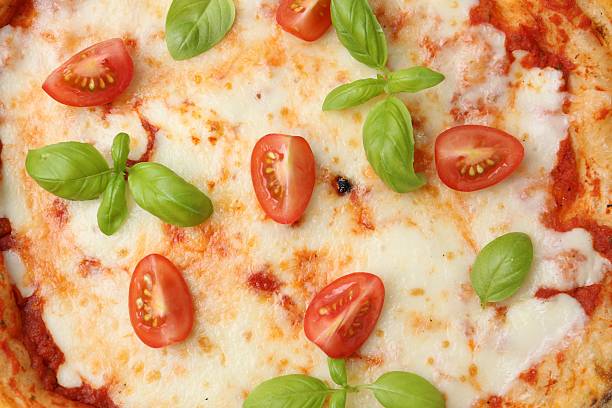Delicious pizza with tomatoes and basil as background, top view