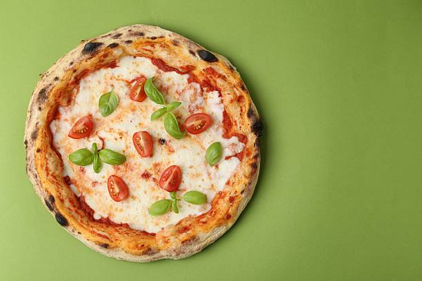 Delicious pizza with tomatoes and basil on green table, top view. Space for text