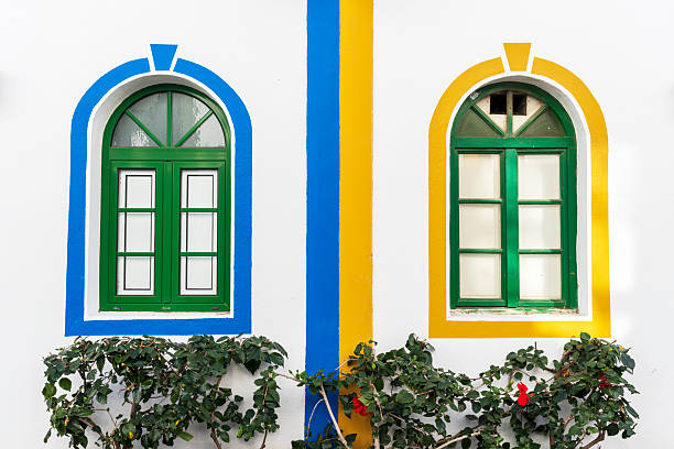 Green arched windows on a white facade surrounded by yellow and blue paint, Gran Canaria, Canary Islands, Atlantic Ocean, Spain