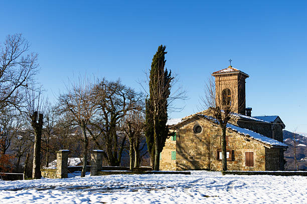 Quiet rural scene showing a historic chapel built from local stone with a snowy path leading to the arched entrance