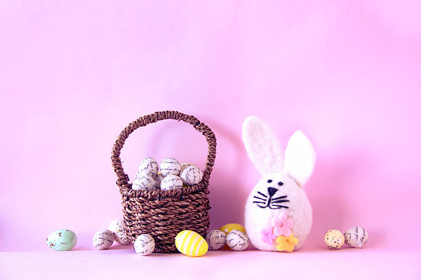 Easter bunny and easter eggs in a basket on pink background.