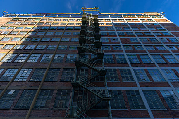 Industrial building with countless windows and a zig zagging fire escape under a blue sky, Zlin