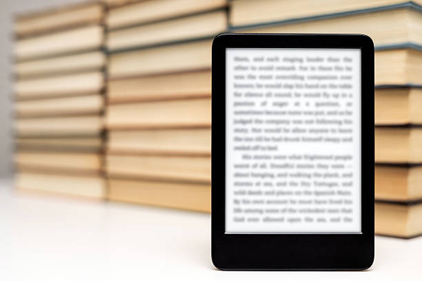 E-book reading concept with hand holding ebook on black table and open traditional paper book. Top view
