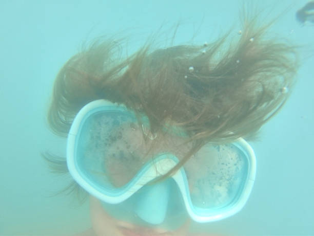Young caucasian boy moving down underwater. He is swimming and diving in clear turquoise colored sea.