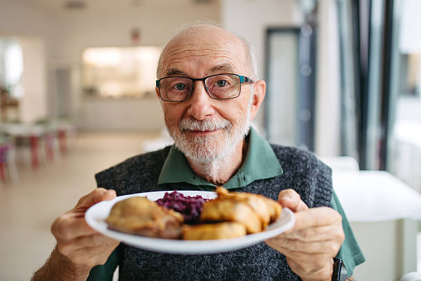 Senior man enjoying lunch at community dining hall. Portrait with copy space.