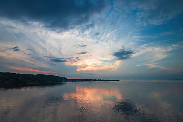 Dnieper river reflecting vibrant sunset colors across its wide surface, with dynamic clouds adorning the sky, creating a tranquil and expansive natural landscape near Cherkasy, Ukraine