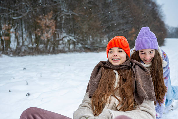 Tobogganing and sledding. Children play and have fun with sledge in winter forest. Running and moving. Happy childhood. Winter holiday. Deep snow. Boys and girls. Warm clothes. Tubing