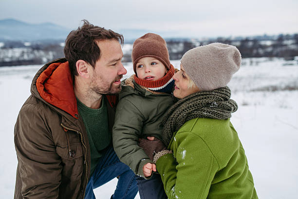 Parents and little son on walk in winter forest.