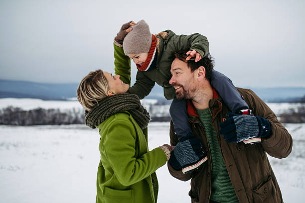 Parents and little son on walk in winter forest.