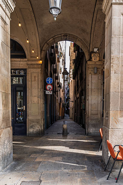 08-28-2022  Barcelona, SP  People walking and sitting in cafe of Barcelona   at narrow street in shadow (hot summer in stone capital city of Catalounia,  Spain)
