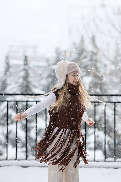 Happy child twirling in falling snow outdoors, expressing joy and freedom during winter. Natural emotions, childhood happiness, seasonal lifestyle, cold weather activity.