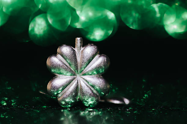 A close-up image showcasing a person's hand holding a green clover-shaped pendant with a matching bead necklace, emphasizing St. Patrick's Day celebration and green aesthetics.