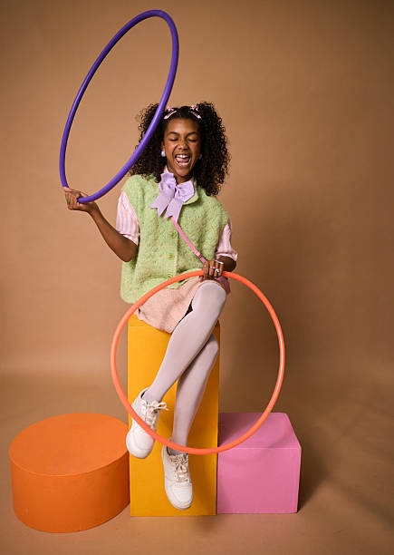 Portrait of beautiful happy and confident Afro-American woman with curly hair smiling and playing with hula hoop outdoors on a public park