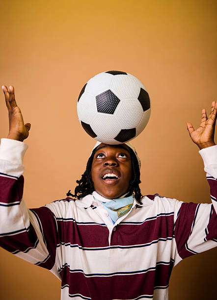 African American elementary age boy making a playful face while holding a soccer ball