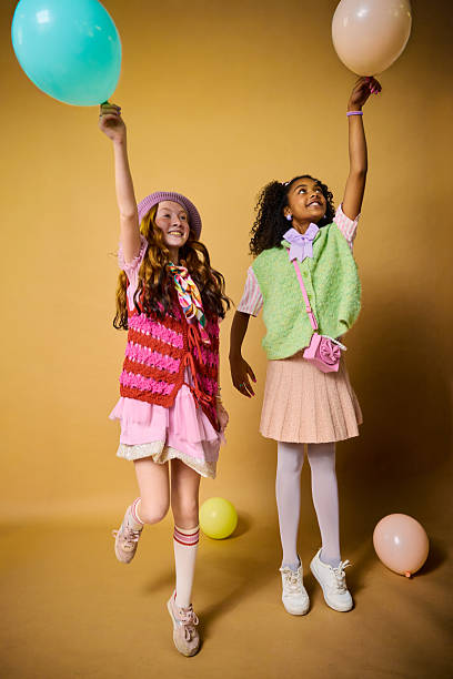 Two cheerful elementary age girls playing with balloons, symbolizing fun and friendship