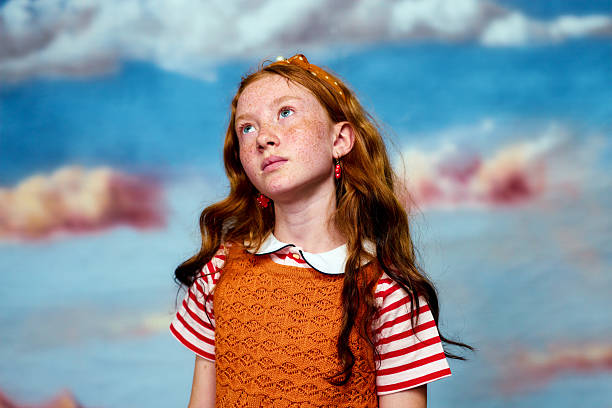 Redhead little girl with freckles looking up with a contemplative expression