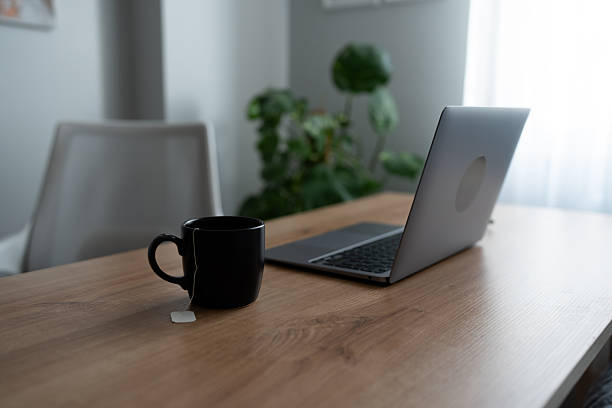 Laptop and tea mug sitting on a wooden desk in a quiet home office environment