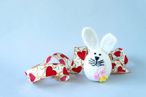 Easter bunny and heart ribbon with gray background.
