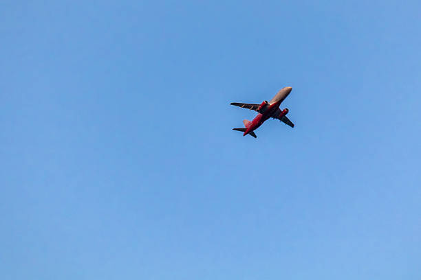 Saint-Petersburg, Russia - 17 May 2025.Passenger airplane flies overhead against clear sky. Aircraft underside and wings visible in frame.