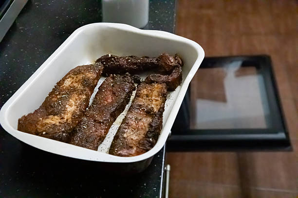 Seasoned meat strips in a white baking dish ready for oven cooking. Culinary preparation concept for home cooked meals and recipes.