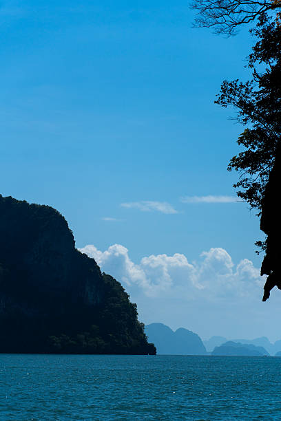 A distant limestone island rising from deep blue water under a clear sky